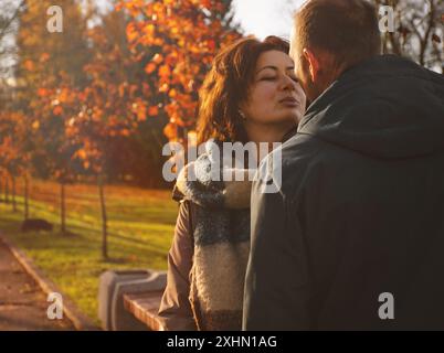 Glückliches verheiratetes Paar, das über 50 Jahre alt ist, spaziert im Herbst an einem warmen sonnigen Tag durch den Park, küsst sich, verbringt einen gemeinsamen Tag. Stockfoto