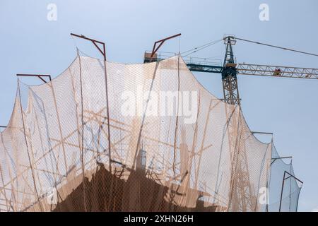 Neubauverfahren. Sicherheitsnetze und Tragbalken heben die laufenden Arbeiten hervor. Detaillierte Aufnahme der Architektur auf mehreren Ebenen. Ideal für Stockfoto