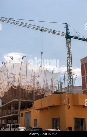Neubauverfahren. Sicherheitsnetze und Tragbalken heben die laufenden Arbeiten hervor. Detaillierte Aufnahme der Architektur auf mehreren Ebenen. Ideal für Stockfoto