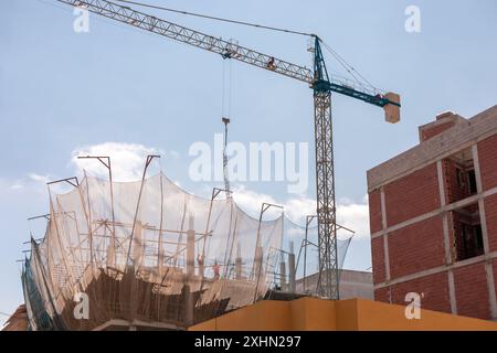 Neubauverfahren. Sicherheitsnetze und Tragbalken heben die laufenden Arbeiten hervor. Detaillierte Aufnahme der Architektur auf mehreren Ebenen. Ideal für Stockfoto