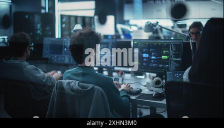 Abteilung für diverse Software-Entwicklung, die in einem Unternehmen für künstliche Intelligenz im Bereich Cybersicherheit arbeitet. Webingenieure, die auf einem Desktop-Computer arbeiten. Von hinten geschossen Stockfoto