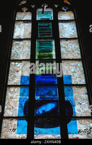 Modernes Buntglasfenster der deutschen Künstlerin Hella de Santarossa in der Heiliggeistkirche in Heidelberg, Baden-Württemberg. Das Fenster zeigt einen Stapel Bücher über einem Laptop und verweist auf eine berühmte Bibliothek, die Biblioteca Palatina, die während des Dreißigjährigen Krieges (1618–1648) aus der Heiliggeistkirche gestohlen wurde. De Santarossa gewann 1997 einen internationalen Designwettbewerb für fünf neue Fenster im Nordschiff. Das Fenster in diesem Bild trägt den Titel „die Welt ist voll des Geistes Gottes“. Stockfoto