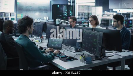 Gruppe von befähigten multikulturellen Männern und Frauen, die in einem Forschungszentrum arbeiten, Computer verwenden, um fortgeschrittene Software auszuführen, Schnittstelle für künstliche Intelligenz und Protokolle für Cyber-Sicherheit zu entwickeln Stockfoto