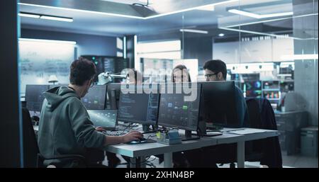 Team aus verschiedenen multiethnischen Softwareentwicklern, die an Computern arbeiten und zusammen in einer Abteilung sitzen. Online-Recherche und Bereitstellung von technischem Support Stockfoto