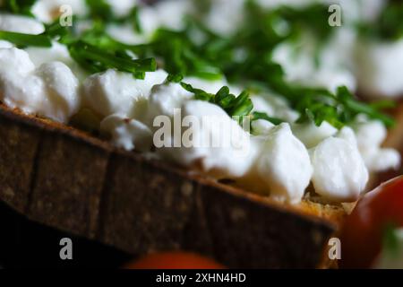 Nahaufnahme von frisch geschnittenem Schnittlauch auf Frischkäse mit geröstetem Brot und Tomaten. Gesunde Bio-Mahlzeit. Stockfoto