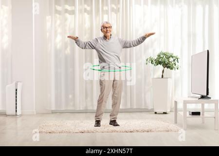 Ein älterer Herr, der zu Hause einen Hula Hoop dreht Stockfoto