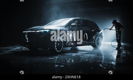 Ein brandneues Elektrofahrzeug aus einer Produktionslinie wird mit einem Wasser-Hochdruckreiniger gereinigt. Fabrikfrische SUV in einer Feinwäsche, bevor sie gewachst und Keramikbeschichtung zum Schutz erhalten Stockfoto