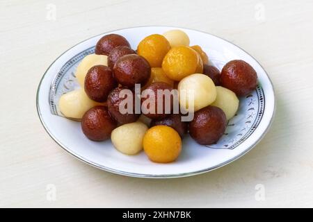 Saftige Bangladeshi-Süßigkeiten auf einem weißen Teller auf hellem hölzernem Hintergrund. Es wird Baby süß genannt, weil es wenig groß ist. Sehr lecker süß. Stockfoto