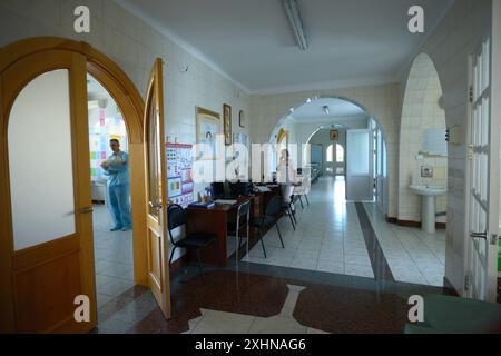 In der Entbindungsabteilung. Arzt hält ein Neugeborenes sichtbar durch eine geöffnete Tür, Krankenschwester sitzt in einer Krankenstation. Juni 2019. Kiew, Ukrainisch Stockfoto