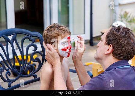 Ein hellhaariger weißer Junge mit blauem Auge hat sein Gesicht mit dem rot-weißen Kreuz von St. George gemalt, das die englische Fußballmannschaft unterstützt Stockfoto