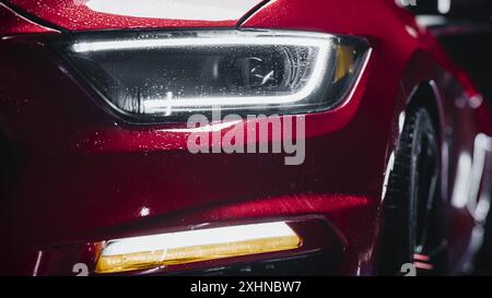 Beauty Nahaufnahme eines roten Sportwagens, der nach einem Detailing-Verfahren austrocknet, oder einer professionellen Autowaschanlage. Aufnahme eines Sport Coupés in Werbequalität mit modernen LED-Leuchten und Retro-Design Stockfoto