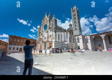 Siena, Italien - 01. Juni 2024: Kathedrale Von Siena. Touristen machen Fotos im Vordergrund. Langbelichtungsaufnahme. Sonniger Tag, klarer Himmel. Stockfoto