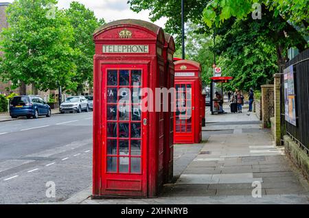 Traditionelle rote britische Telefondosen auf dem Bürgersteig an der Elgin Avenue in London, Großbritannien Stockfoto