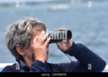 Eine ältere Frau, die durch das Fernglas schaut. Die Schönheit des Golfs von Morbihan, Bretagne. Frankreich Stockfoto