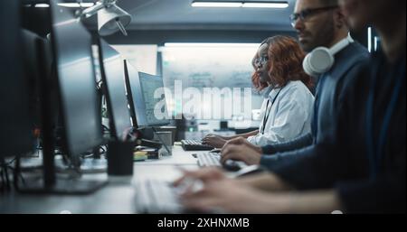 Fokussierte junge afroamerikanische weibliche Software-Entwicklerin, die zusammen mit zwei kreativen männlichen Kollegen am Computer arbeitet. Data Protection Center mit Servern, Speicherhardware und eBusiness Research Stockfoto