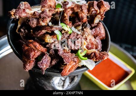 Shekla Tibs ist eine herzhafte äthiopische Nationalmahlzeit aus sautiertem Fleisch und Gewürzen, die traditionell in einem Tontopf mit Injera serviert wird Stockfoto