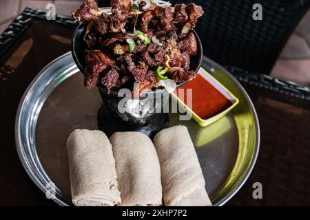 Shekla Tibs ist eine herzhafte äthiopische Nationalmahlzeit aus sautiertem Fleisch und Gewürzen, die traditionell in einem Tontopf mit Injera serviert wird Stockfoto