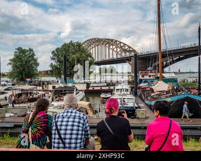 Man sieht Menschen, die auf die Boote im Hafen schauen. Das Vierdaagsefeesten ist die größte frei zugängliche Veranstaltung in den Niederlanden und die viertgrößte Veranstaltung in Europa. Diese Veranstaltung findet gleichzeitig mit den International Four Days Marches statt, dem weltweit größten mehrtägigen Wandertag. Jedes Jahr präsentiert diese Veranstaltung ein vielseitiges Programm mit mehr als 1000 Acts auf mehr als 45 Bühnen, die alle kostenlos sind und die Menschen zu mehr als 1,5 Millionen Besuchen in der Innenstadt von Nijmegen in den Niederlanden anlocken. (Foto: Ana Fernandez/SOPA Images/SIPA USA) Stockfoto