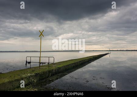 Auslaufleitung in Langstone Harbour, Hampshire, Großbritannien. Dramatischer Himmel Stockfoto