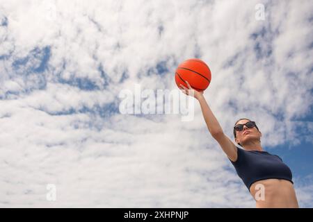 Eine sportliche Frau, die gerade einen Basketball schießen will, aus einem tiefen Winkel Stockfoto