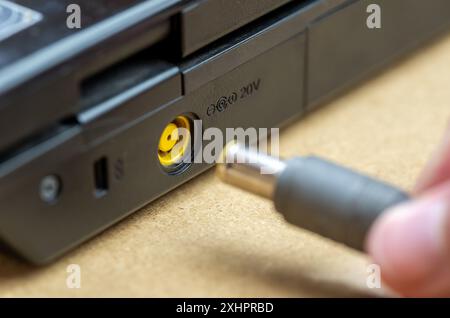 Mannerhand einstecken Anschließen eines Netzadapterkabels an einen normalen Laptop-Computer anschließen und den Akku eines Laptops mit 20 V aufladen Stockfoto