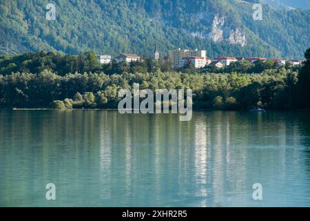 Ein wunderschöner See mit einer Stadt im Hintergrund. Das Wasser ist ruhig und das Spiegelbild der Stadt ist sichtbar Stockfoto