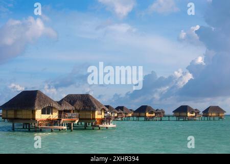 Französisch-Polynesien, Insel Taha'a, Bungalows auf Stelzen, die auf der Lagune des Taha'a Pearl Resort Hotels vor einem blauen und bewölkten Himmel liegen Stockfoto