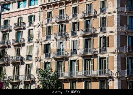 Vorderfassade eines Apartmentblocks in Barcelona, Spanien, mit vielen Fenstern, Balkonen und bunten Holzläden Stockfoto