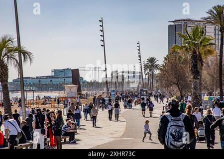 Überfüllte Menschenmassen laufen entlang der Strassen am Strand in Barcelona, Spanien Stockfoto