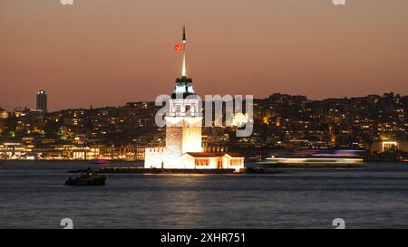 Langzeitaufnahme des Mädchenturms - Kız Kulesi in Istanbul. Die unscharfe Bewegung eines Bootes auf dem Wasser verleiht der Nacht ein dynamisches Element. Stockfoto