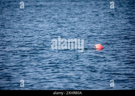 Orange/rote Markierungsboje allein mitten im Wasser in einem ruhigen blauen Ozean, keine Leute, Kopierraum/Kopierraum Stockfoto