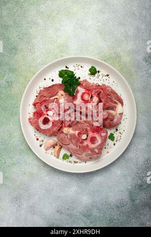 Rohes Steak, Kalbhals auf den Knochen, frisches Fleisch, auf einem weißen Teller, Blick von oben, keine Leute Stockfoto