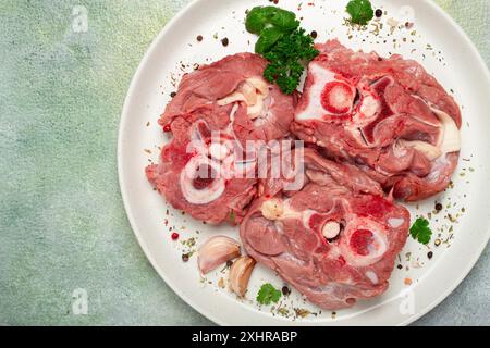 Rohes Steak, Kalbhals auf den Knochen, frisches Fleisch, auf einem weißen Teller, Blick von oben, keine Leute Stockfoto