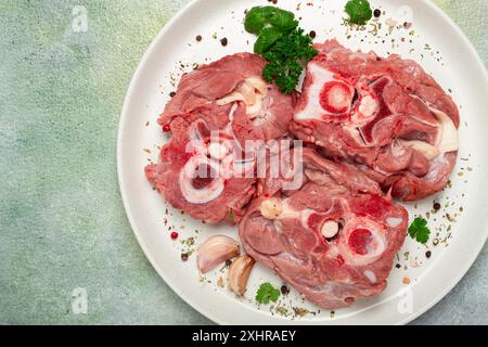 Rohes Steak, Kalbhals auf den Knochen, frisches Fleisch, auf einem weißen Teller, Blick von oben, keine Leute Stockfoto