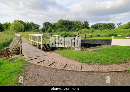 Das Monument Lock Tore und kleine weiße Holzbrücke, der Kennett & Avon Canal bei Devizes. Vom Juli 2024. Sommer. Stockfoto