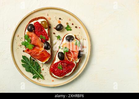 Sandwiches mit Käse und Schinken, getrockneten Tomaten und Oliven, Frühstück auf einem Teller Stockfoto