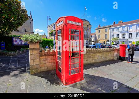 Alte Telefonzelle und Mann, der einen Brief in einem alten roten Briefkasten postet, Devizes Stadtzentrum. Vom Juli 2024. Sommer. Stockfoto