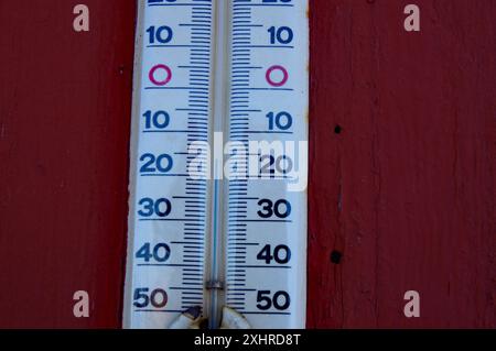 Eine Nahaufnahme eines weißen Thermometers, das die Temperatur mit rotem Holzhintergrund anzeigt, Winter, Abisko, Lappland, Schweden Stockfoto