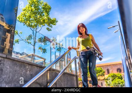 Niedriges Foto einer chinesischen jungen Frau mit Skateboard, die die Treppe hinunter geht Stockfoto