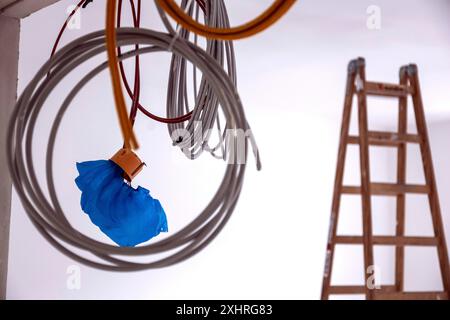 Kabel, die an einer Baustelle an einer Wand hängen, im Hintergrund eine Leiter, Berlin, 03.07.2024., Berlin, Berlin, Deutschland Stockfoto