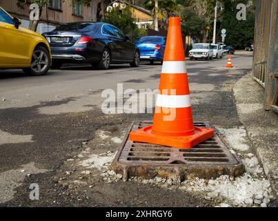 Sotschi, Russland - 16. Februar 2023: Markiert durch einen Kegel, der vorstehende Teil eines Sturmgitters auf einer Straße, die repariert wird Stockfoto