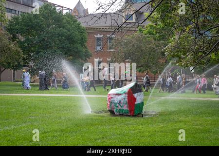 Detroit, Michigan, USA. Juli 2024. Interreligiöse Führer versammelten sich an der Wayne State University, um sich zu versammeln und für Frieden in Gaza zu beten. Sie baten die Universität, sich von Unternehmen zu veräußern, die von Krieg und Waffenherstellung profitieren. Die Universität schaltete Rasensprenger rund um Spirit Rock ein, wo sie sich sammeln wollten. Spirit Rock war der Ort eines Antikriegslagers für Studenten, das die Universitätspolizei im Mai abbrach. Quelle: Jim West/Alamy Live News Stockfoto