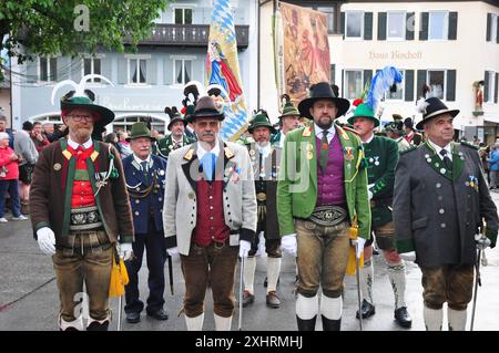 Männer in traditioneller bayerischer Tracht stehen auf einem Dorfplatz, umgeben von alten Gebäuden, Garmisch-Partenkirchen, Alpenregion Stockfoto