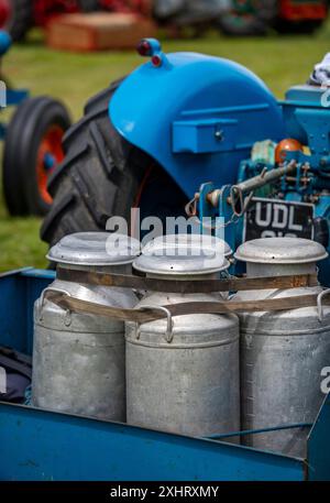 Eine Reihe von altmodischen Metallmilchkannen im Vintage-Stil auf der Rückseite eines Vintage-Traktors auf der isle of wight County Show in großbritannien Stockfoto