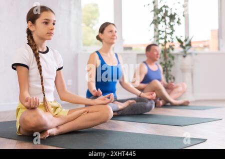 Teenager-Mädchen mit ihren Eltern praktiziert Yoga in Lotusposition Stockfoto