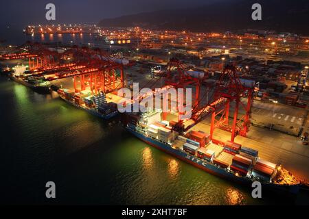 LIANYUNGANG, CHINA - 15. JULI 2024 - Frachtschiffe entladen Container am Containerterminal des Hafens Lianyungang, Provinz Jiangsu im Osten Chinas, Juli Stockfoto