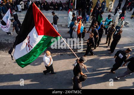 Ein kaschmirischer schiitischer Mann geht mit einer palästinensischen Flagge, die mit „Mazloom“ beschriftet ist, während einer Prozession am achten Tag von Muharram. Im zweiten Jahr in Folge erlaubte die Regierung von Jammu und Kaschmir die 8. Muharram-Prozession vom Guru-Basar nach Dalgate in Srinagar. Trotz eines seit langem bestehenden Verbots hielten die schiitischen Muslime weiterhin Prozessionen auf dem 8. Und 10. Muharram entlang dieser Routen ab, die oft mit Polizeieingriffen konfrontiert waren. Die diesjährige Prozession war ein bedeutendes und friedliches Gedenken an das Martyrium von Hazrat Imam Hussainís (AS), das Tausende von Trauernden anzog. Die Prozession Stockfoto