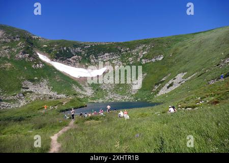 REGION ZAKARPATTIEN, UKRAINE - 14. JULI 2024 - Touristen werden am höchsten Bergsee der Ukraine, Brebeneskul, gesehen, wo trotz der Temperatur von 35°C der Schnee noch nicht geschmolzen ist, im Karpaten-Biosphärenreservat, Bezirk Rakhiv, Region Zakarpattien, Westukraine Stockfoto