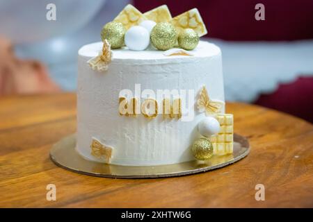 Dekorierter weißer Kuchen zum Geburtstag der Mutter wurde aus einem anderen Blickwinkel am Tisch drinnen aufbewahrt Stockfoto