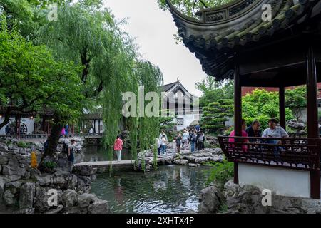 Shanghai, China - 6. Juni 2024 : Ein heiterer Teich mit einer Steinbrücke im Yu-Garten, Shanghai, China. Üppiges Grün und traditionelles Architekturkrea Stockfoto
